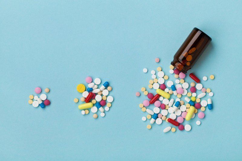A bottle of pills is pouring out of it on a blue background.